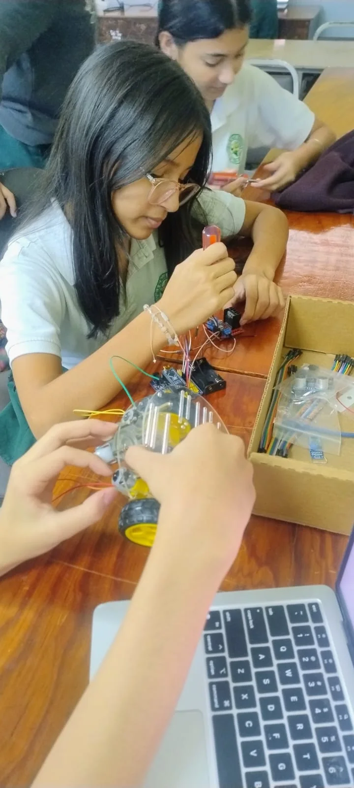 Students connecting electronics on a mobile robot